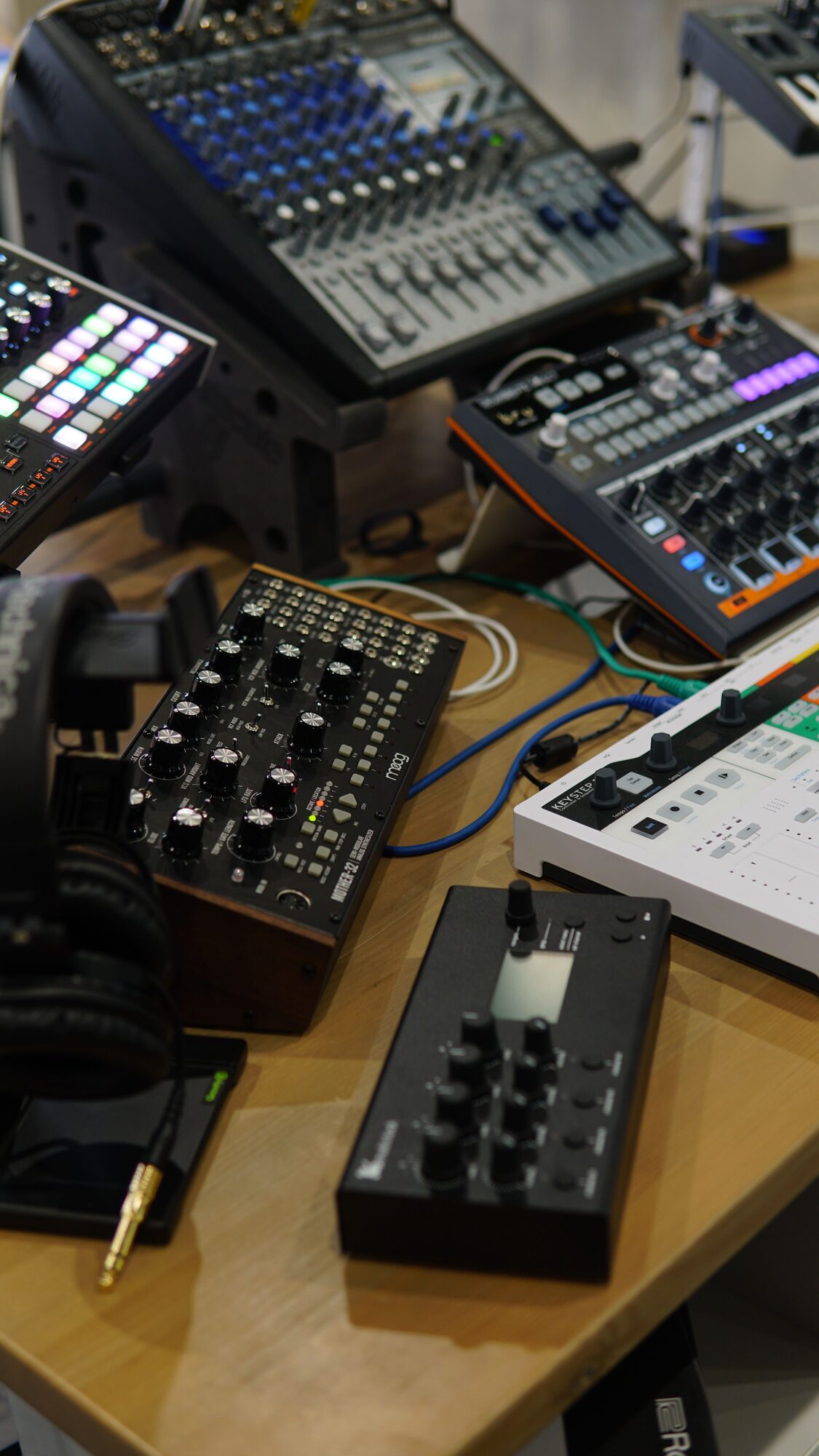 Mixer and synth gear stacked in a studio