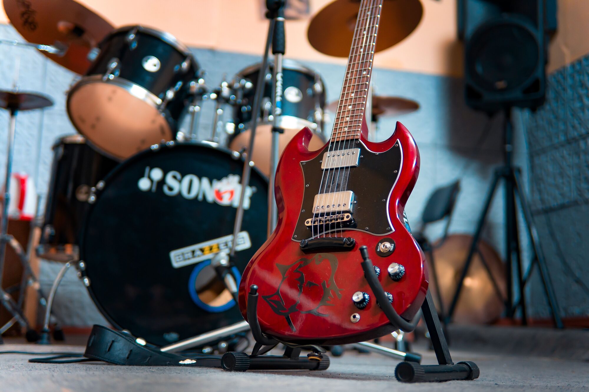 Red electric guitar and drum kit in a rehearsal room