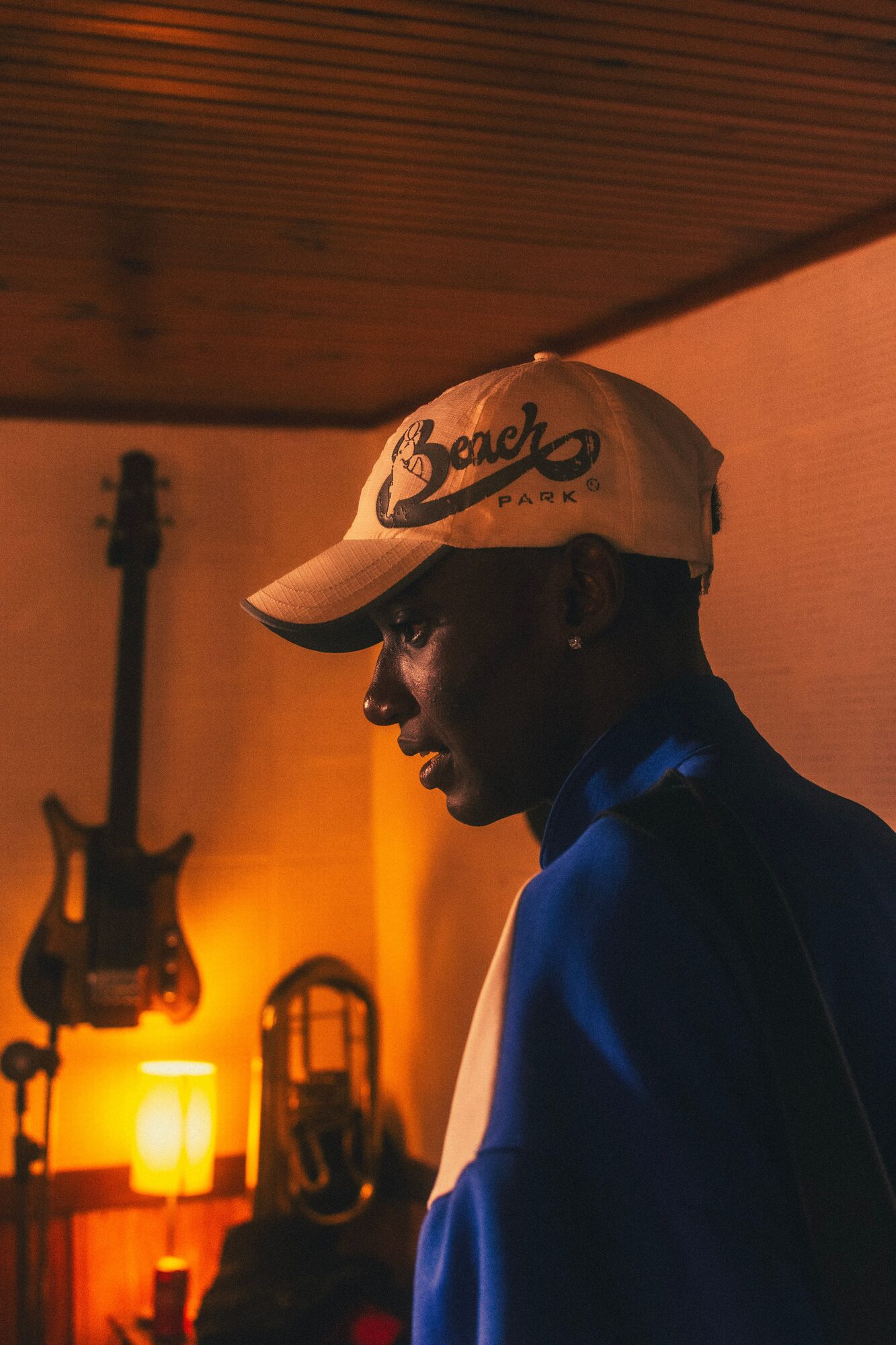 Musician in a warm amber-lit room with guitar and lamp