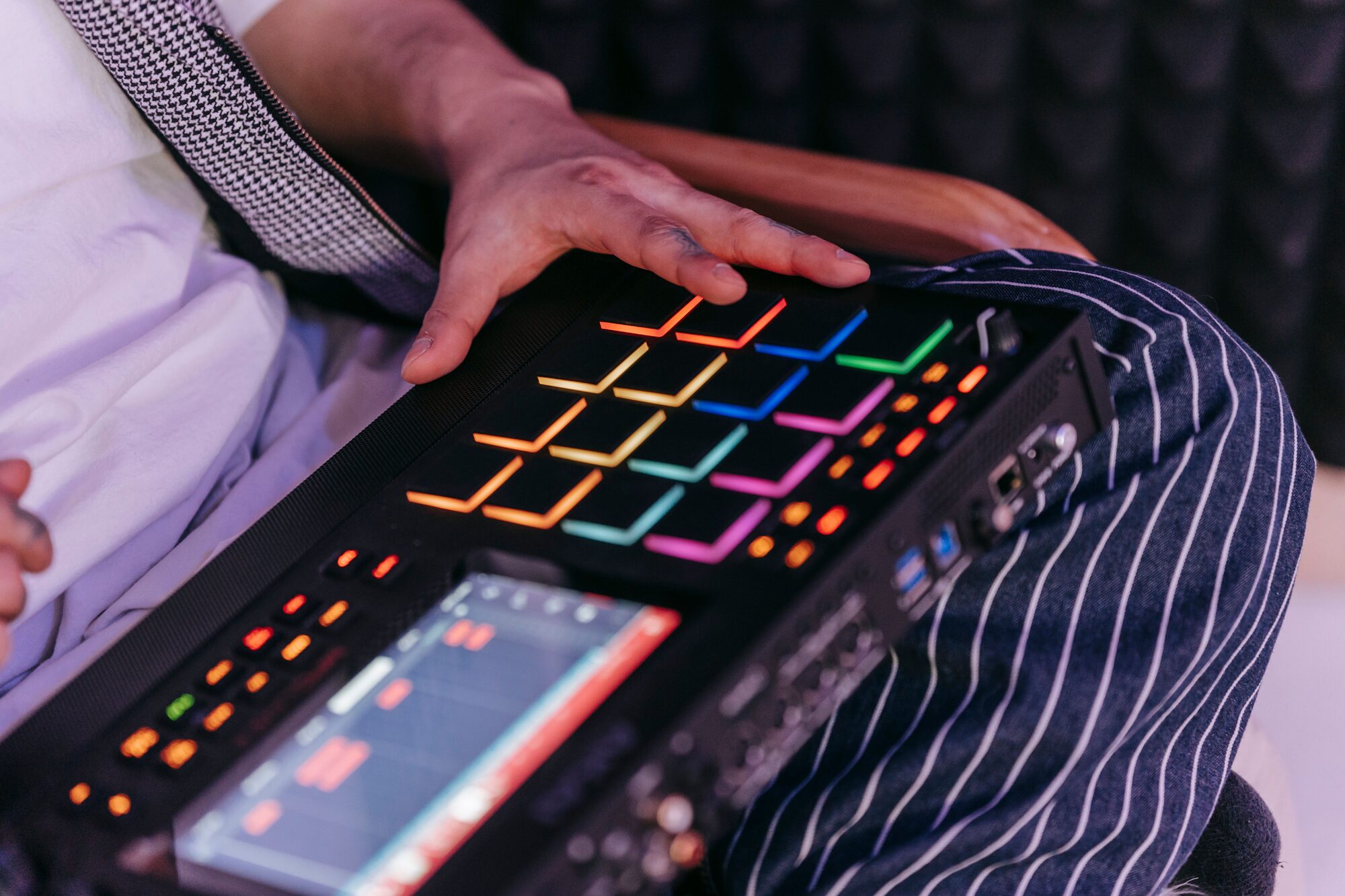 Producer hitting glowing drum pads on a sampler