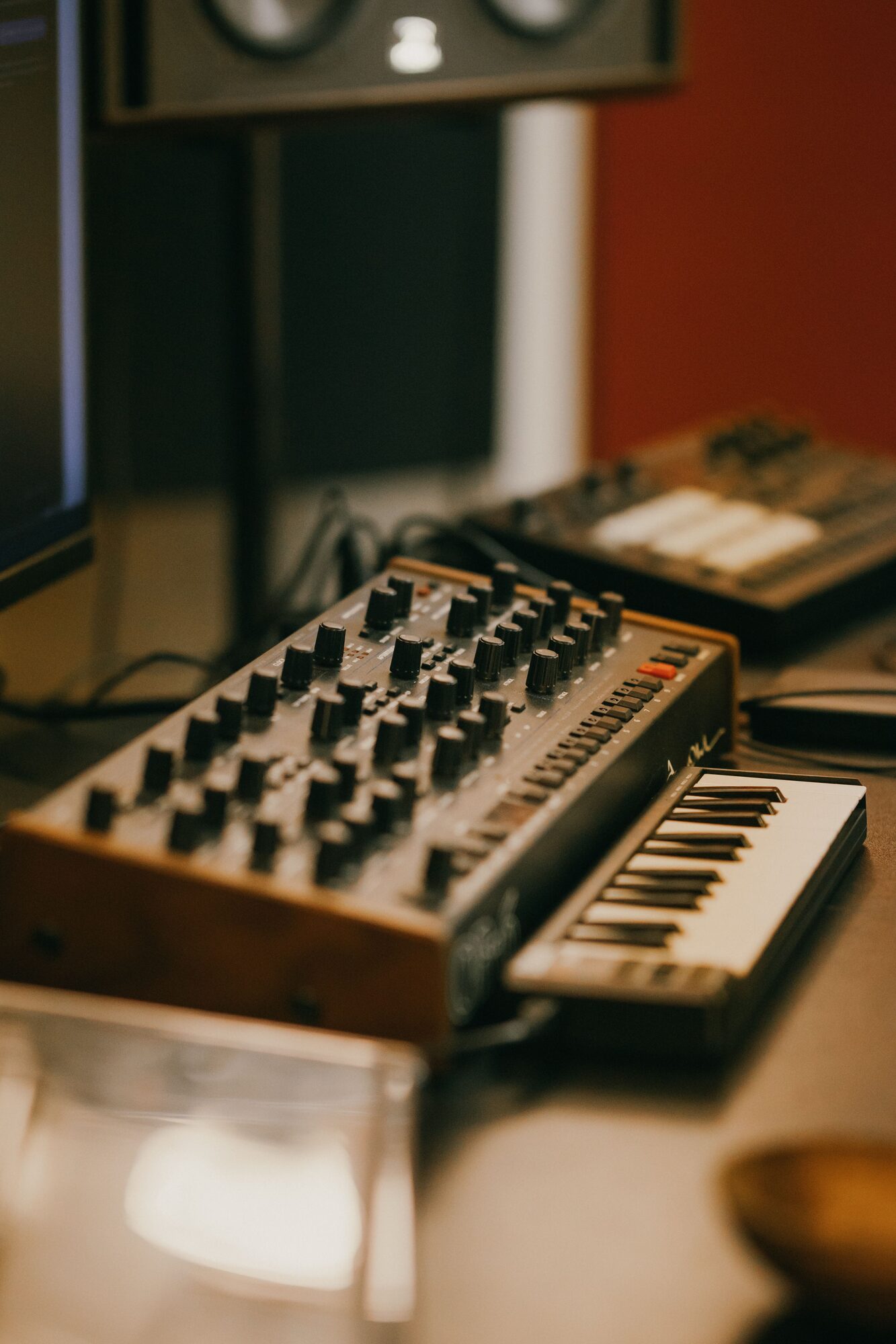Wooden-panelled synthesizer and monitors on a warm desk