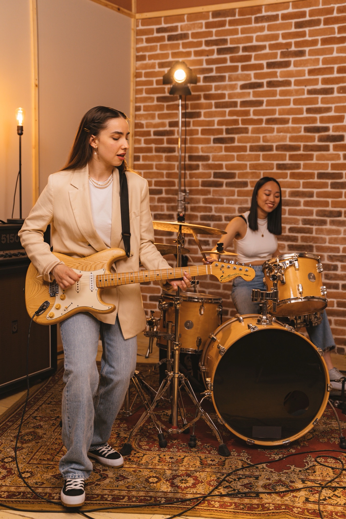 Guitarist and drummer in a brick-walled room