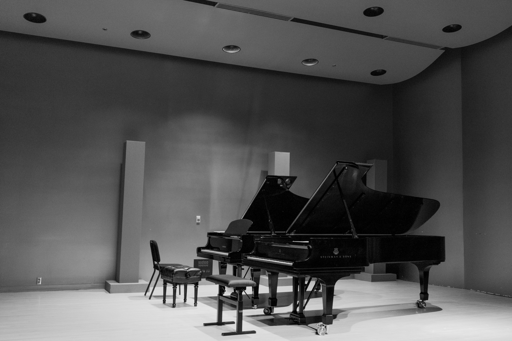 Two grand pianos on a recital stage, black and white