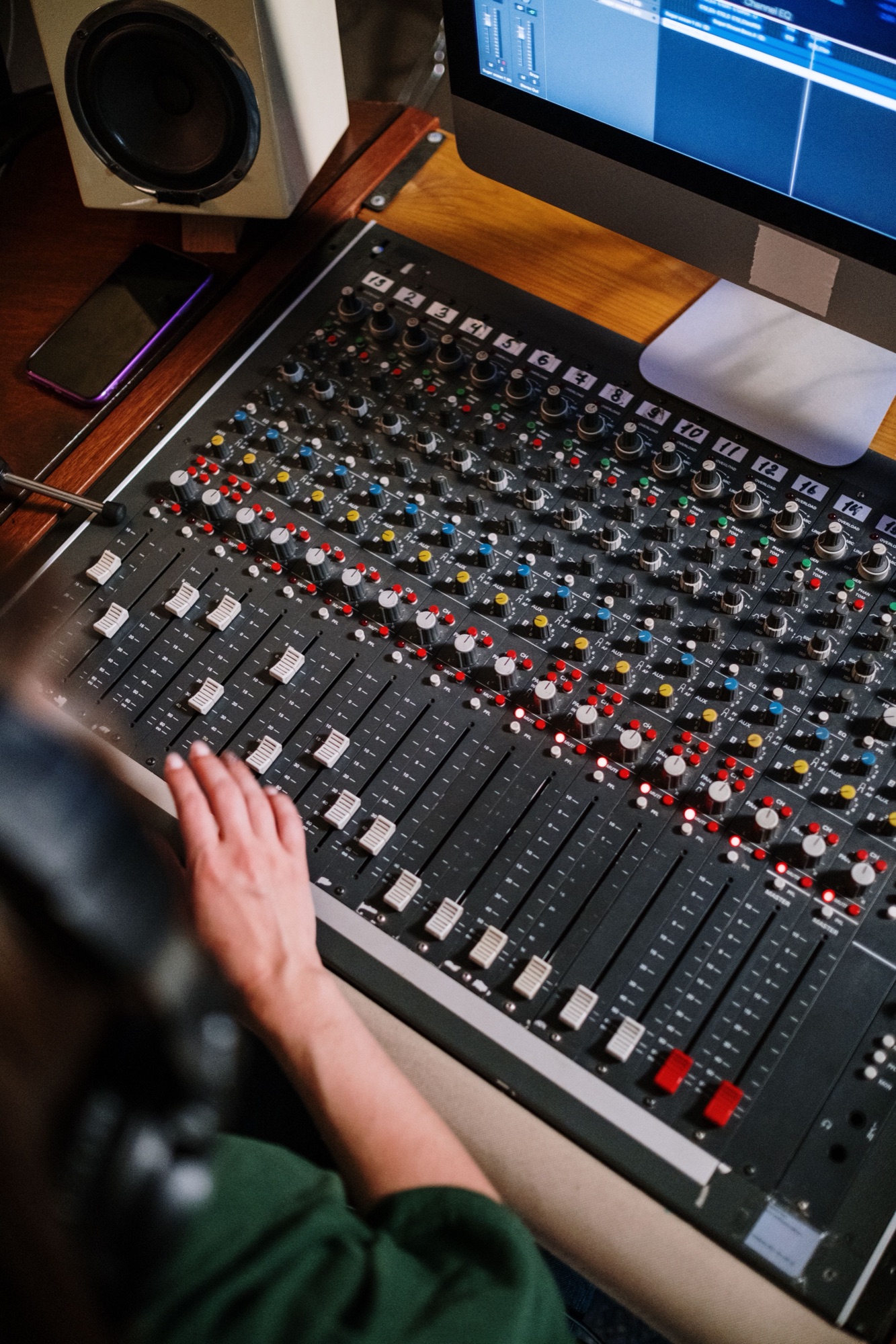 Hand adjusting faders on a recording console